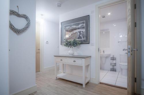 a white bathroom with a sink and a toilet at Minarvon - 2 Bedroom Apartment - Saundersfoot in Saundersfoot