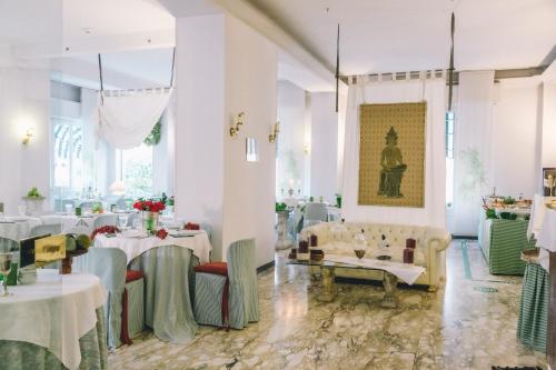 ein Esszimmer mit weißen Tischen und Stühlen in der Unterkunft Eveline Portosole Hotel in Sanremo