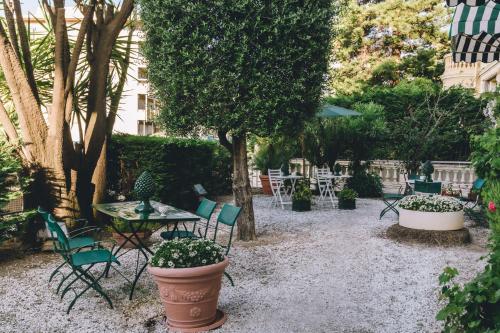 a garden with chairs and tables and plants at Eveline Portosole Hotel in Sanremo