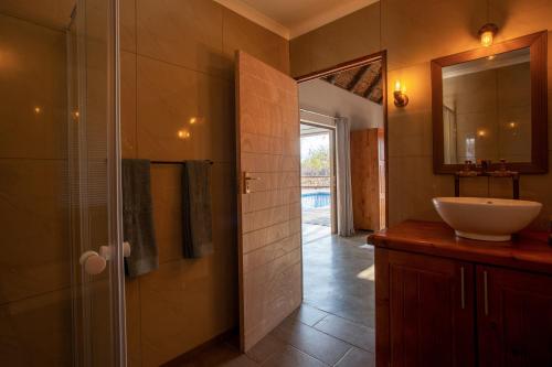 a bathroom with a sink and a mirror at Vuyani Marula Lodge in Hoedspruit