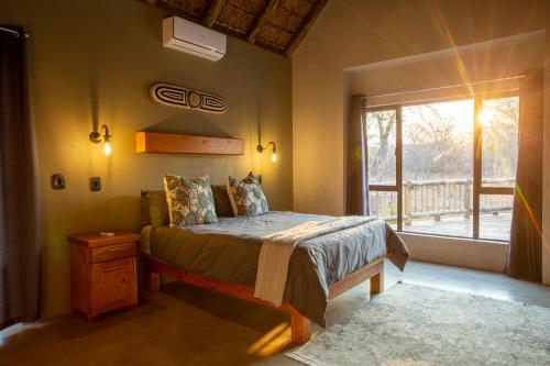 a bedroom with a bed in a room with a window at Vuyani Marula Lodge in Hoedspruit