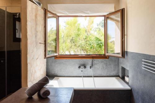 ein Bad mit einer Badewanne und einem Fenster in der Unterkunft Lavish Ibizan Villa Beautiful Gardens Villa Izarra Located Between San Antonio and San Jose in Cala de Bou