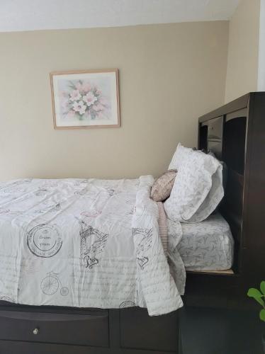 - un lit avec des draps blancs et une photo sur le mur dans l'établissement Entire Guesthouse 5 mins to Siesta Key & downtown, à Sarasota