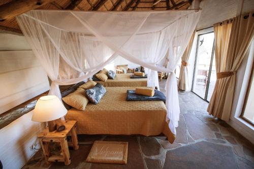 a bedroom with two beds with a canopy at Huab Lodge & Bush Spa in Konob Pos