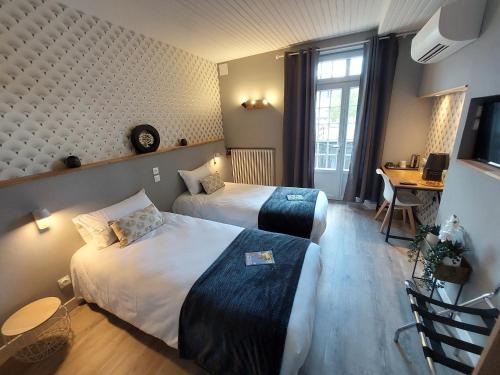 Habitación de hotel con 2 camas y escritorio en Logis Loire Hotel - Les Cocottes Restaurant, en Les Rosiers