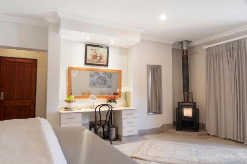 a bedroom with a bed and a desk and a fireplace at Rueby’s Guesthouse in Dullstroom
