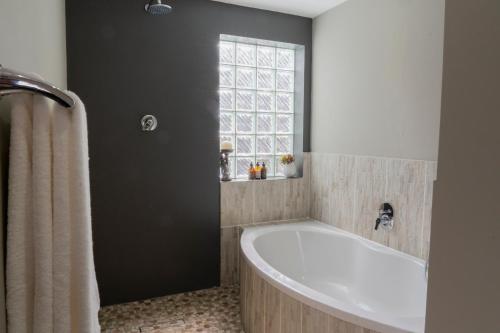 a bathroom with a bath tub and a window at Rueby’s Guesthouse in Dullstroom