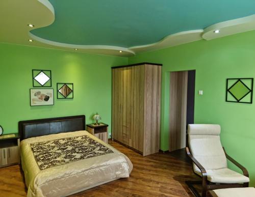 1 dormitorio con paredes verdes, 1 cama y 1 silla en Apartment Maya, en Visaginas