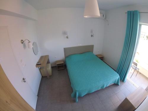 a small bedroom with a green bed and a window at Kimiro Drosia Zante in Psarou