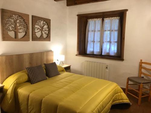 1 dormitorio con 1 cama amarilla, ventana y silla en la Caseta Boi Taull - 2 habitaciones, en Pla de l'Ermita