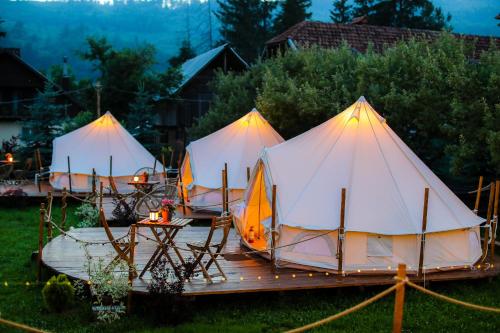 um grupo de três tendas sentadas num convés em Valea Doftanei Glamping em Teşila