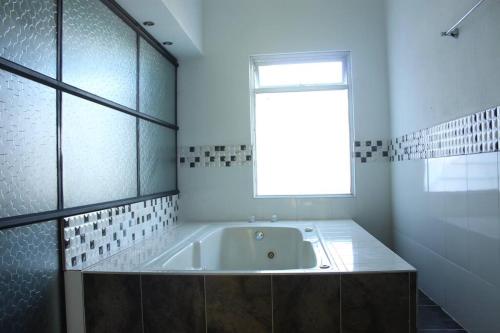ein weißes Bad mit einer Badewanne und einem Fenster in der Unterkunft Villa Natalia Finca, 30 personas, jacuzzi 10 minutos de termales in Santa Rosa de Cabal