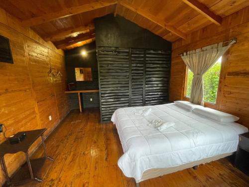 ein Schlafzimmer mit einem großen weißen Bett in einem Holzzimmer in der Unterkunft Grandpas Hotel & Restaurante in Cartago