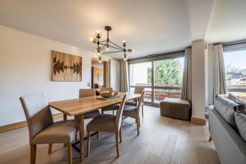 uma sala de jantar com uma mesa e cadeiras e um sofá em Apartment Cortirion Megeve - by EMERALD STAY em Megève