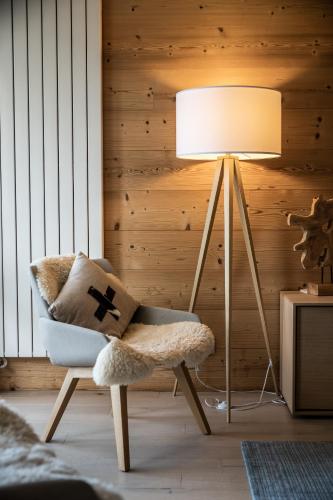 a lamp in a room with a chair with a pillow at Apartment Cortirion Megeve - by EMERALD STAY in Megève