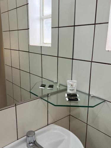 Baño con estante de cristal sobre un aseo en Europa Hotel Brasília, en Taguatinga