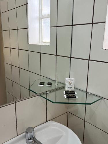 a bathroom with a glass shelf above a toilet at Europa Hotel Brasília by Bsb Inn in Taguatinga
