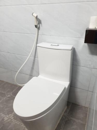 a white toilet in a bathroom with a hose at THANH XUÂN HOTEL in Cao Bằng