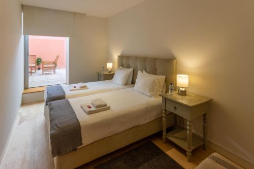 a bedroom with a bed with a table and a window at Garça Real Flats in Porto
