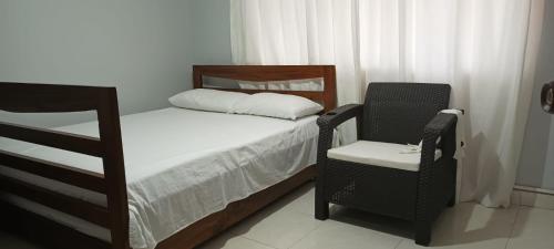 een kleine slaapkamer met een bed en een stoel bij Apartamento con linda terraza en San Antonio in Cali