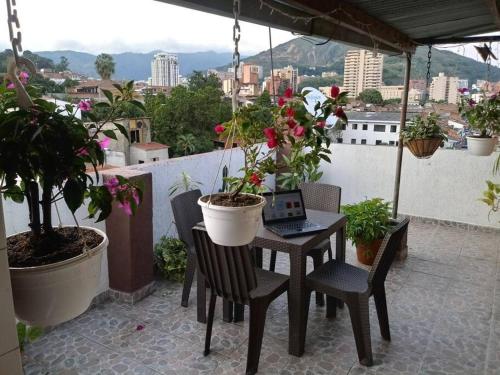 a table with a laptop on a balcony with potted plants at Apartamento con linda terraza en San Antonio in Cali