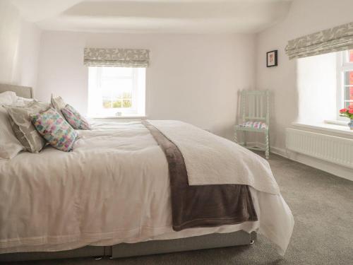a bedroom with a bed with a window and a chair at Rose Cottage in Clitheroe