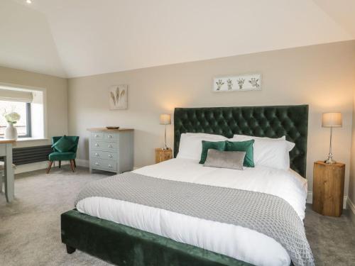 a bedroom with a large bed with a green headboard at Fox's Den in Hull