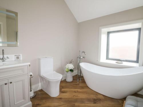 a bathroom with a tub and a toilet and a window at Fox's Den in Hull