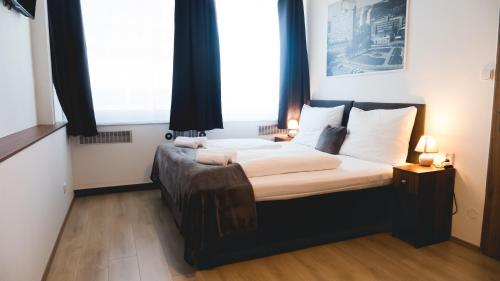1 dormitorio con 1 cama grande y 2 ventanas en Hotel U Ševce, en Zlín