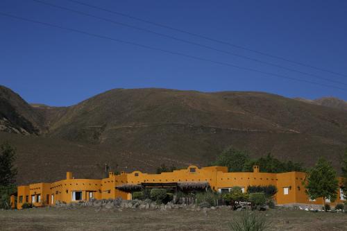 a large yellow building in front of a mountain at Posada La Guadalupe in Tafí del Valle