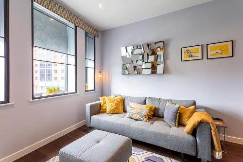 a living room with a gray couch and windows at Exmouth Market Apartment in London