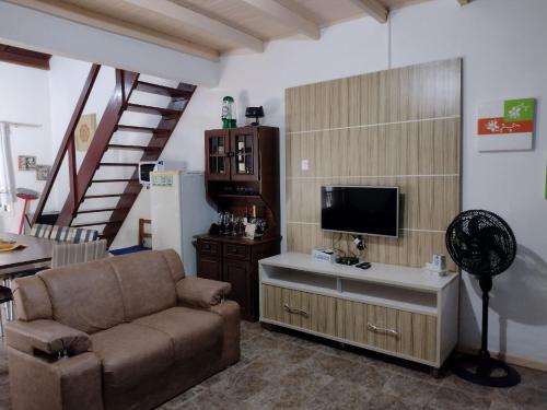 un soggiorno con divano, TV e scala di Pousadinha e Residencial Sto António - Praia de Bombas/Bombinhas-SC a Bombinhas