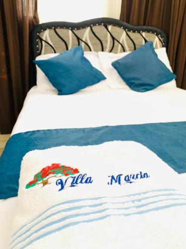 a bed with blue and white sheets and blue pillows at Villa Marcia in Boca Chica
