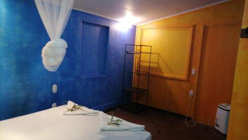 a room with a bed and a blue wall at La Palapa Hut Nature Hostel in Puerto Jiménez