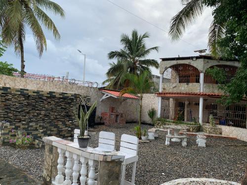 a yard with two white chairs and a building at Villa Marcia in Boca Chica