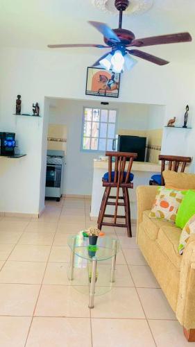 a living room with a ceiling fan and a table at Villa Marcia in Boca Chica