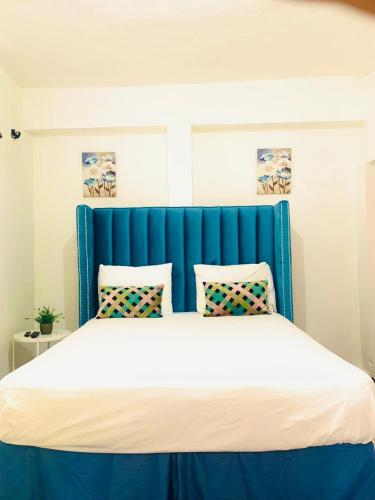 a bed with a blue headboard and two pillows at Villa Marcia in Boca Chica