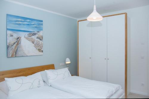 a bedroom with a bed and a painting on the wall at Cottage im Gutspark, Perlie - Komfort trifft maritimes Flair in Rerik