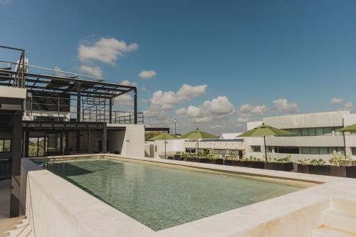 una piscina en la azotea de un edificio con sombrillas en Caleta Hostel Rooftop & Pool, en Cancún