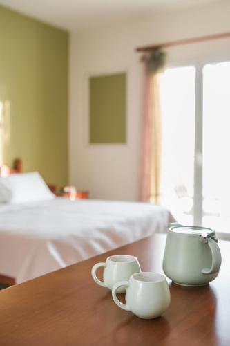 two coffee cups sitting on a table in a bedroom at Eagle's Nest in Lourdhata