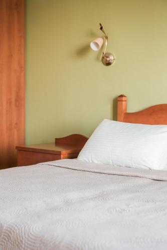 a bedroom with a white bed with a lamp on the wall at Eagle's Nest in Lourdhata