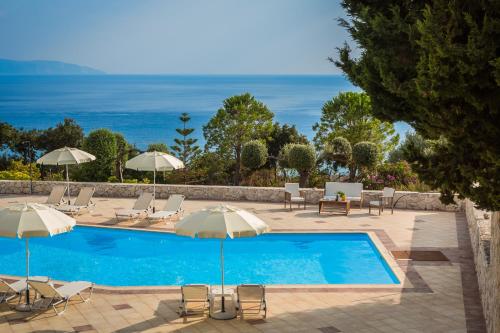 a swimming pool with umbrellas and chairs and the ocean at Eagle's Nest in Lourdhata