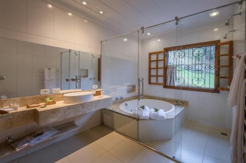 a bathroom with a tub and a sink and a window at Quinta dos Pinhais Pouso e Charme in Santo Antônio do Pinhal