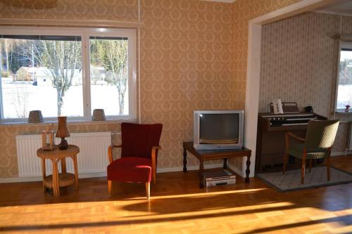 a living room with a tv and chairs and a piano at Countryside Holiday home "Our Little Farm" in Hagfors