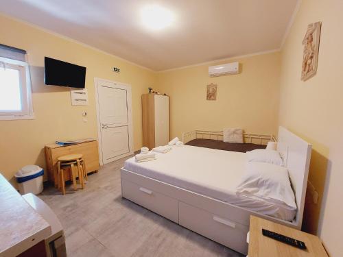 een slaapkamer met een bed, een bureau en een televisie bij George studios 1 in Ýpsos