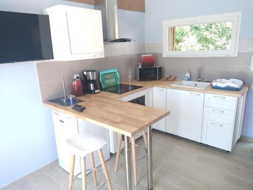 a kitchen with white cabinets and a wooden counter top at eco nature, gite à la ferme in Vendays-Montalivet