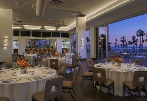 a restaurant with white tables and chairs with a view at Paséa Hotel & Spa in Huntington Beach