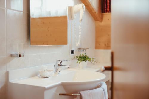 a bathroom with a white sink and a phone at Oberaldoss Residence Wellness in Santa Cristina in Val Gardena