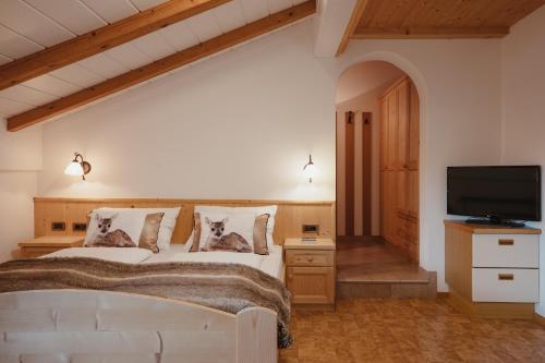 a bedroom with a white bed and a flat screen tv at Oberaldoss Residence Wellness in Santa Cristina in Val Gardena