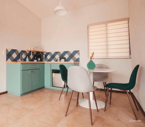 una cocina con armarios verdes, mesa y sillas en Huella B, en Guadalupe